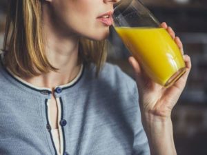 mulher bebendo suco de laranja
